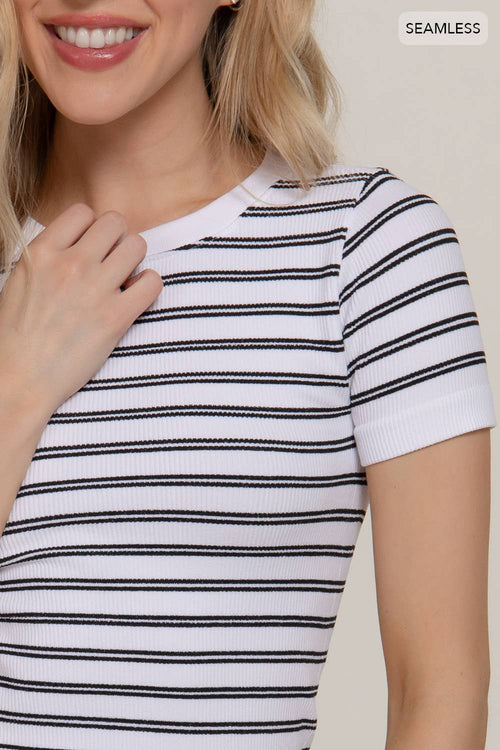 Woman wearing a white and black striped shirt with a plain background