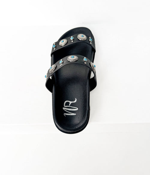 Black sandal with decorative studs on a white background