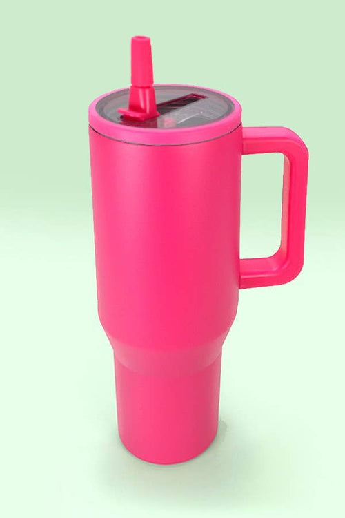 Pink insulated mug with handle and straw on a light green background