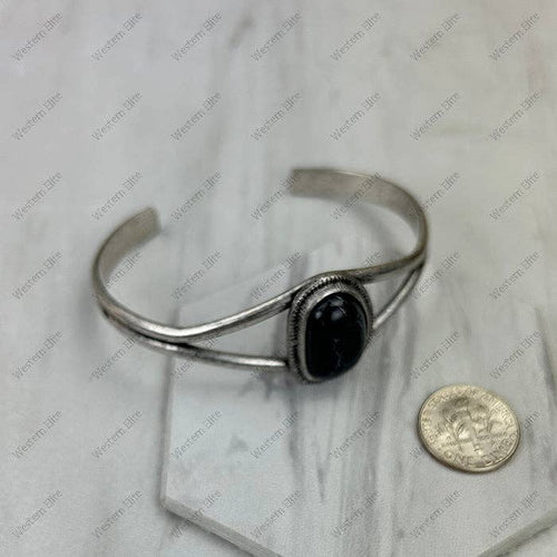 Silver bracelet with a black stone on a marble surface