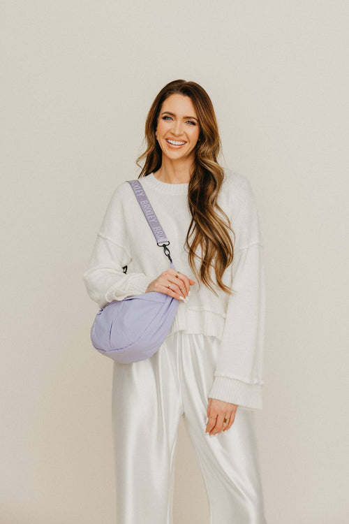 Woman holding a purple bag against a plain background