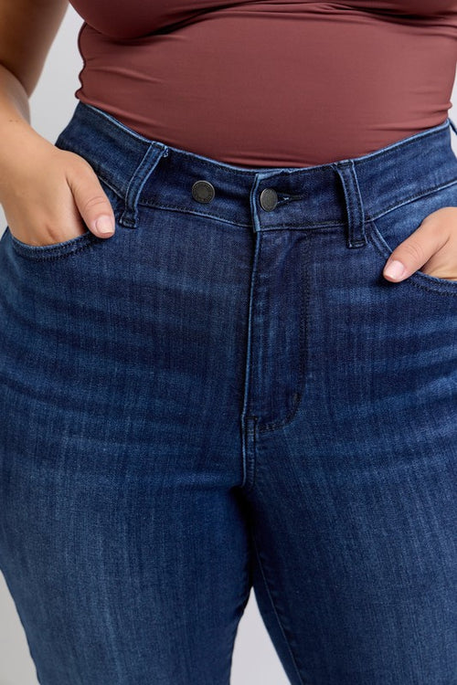 Person wearing blue jeans and a brown top on a plain background