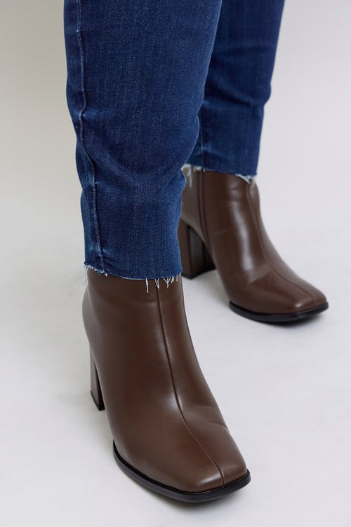 Brown ankle boots worn with blue jeans on a white background