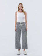 Woman wearing a white tank top and leopard print pants on a white background