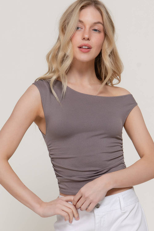Woman wearing a brown off-shoulder top against a plain background