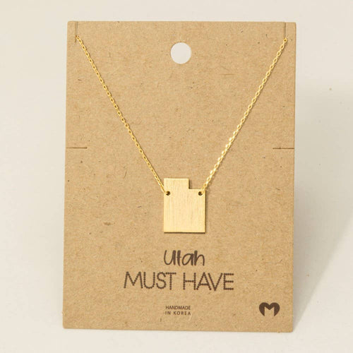 Gold necklace with a square pendant on a brown card with 'Utah MUST HAVE' text.