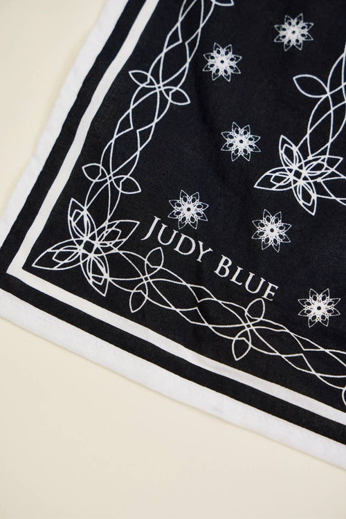 Black fabric with white floral patterns and 'Judy Blue' branding on a beige background