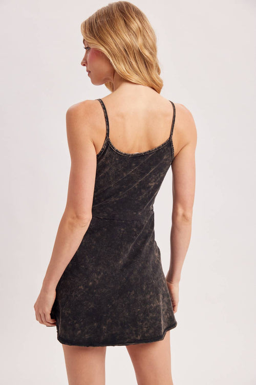 Woman wearing a black sleeveless dress against a plain background