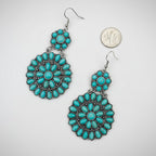 Turquoise earrings with silver hooks on a white surface.