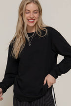 Woman wearing a black sweater against a plain background