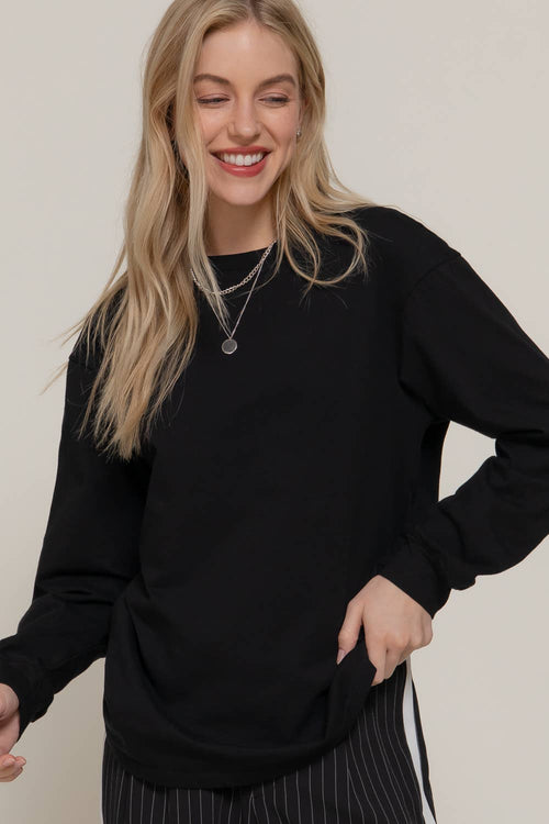 Woman wearing a black sweater against a plain background