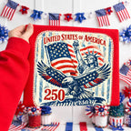 Card with 'United States of America 250th Anniversary' design held by a person in a red sleeve, with American flags and decorations in the background.