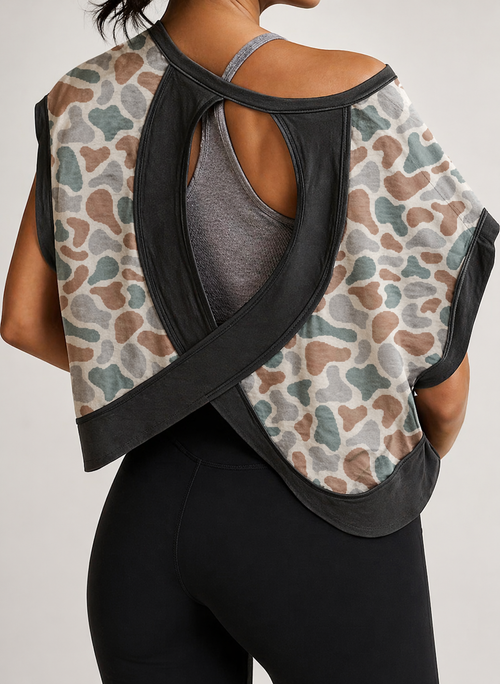 Person wearing a patterned sleeveless top with black straps over a gray tank top on a light gray background