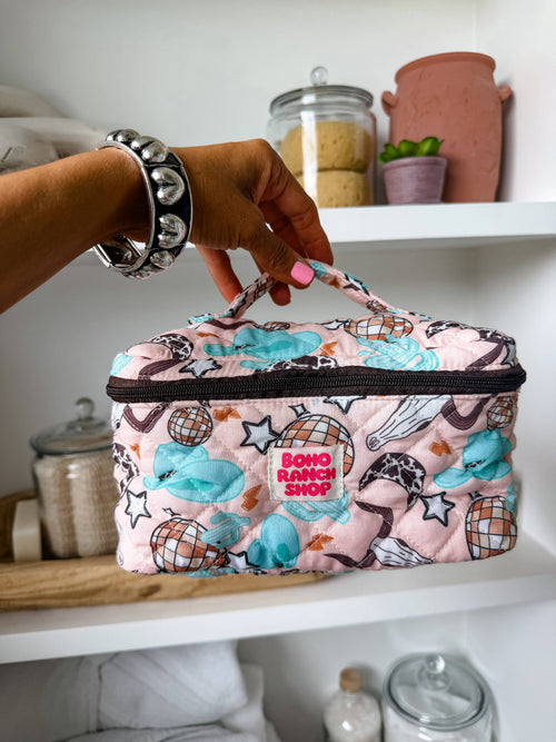Person holding a patterned lunch bag with 'Boho Ranch shop' text on a shelf.