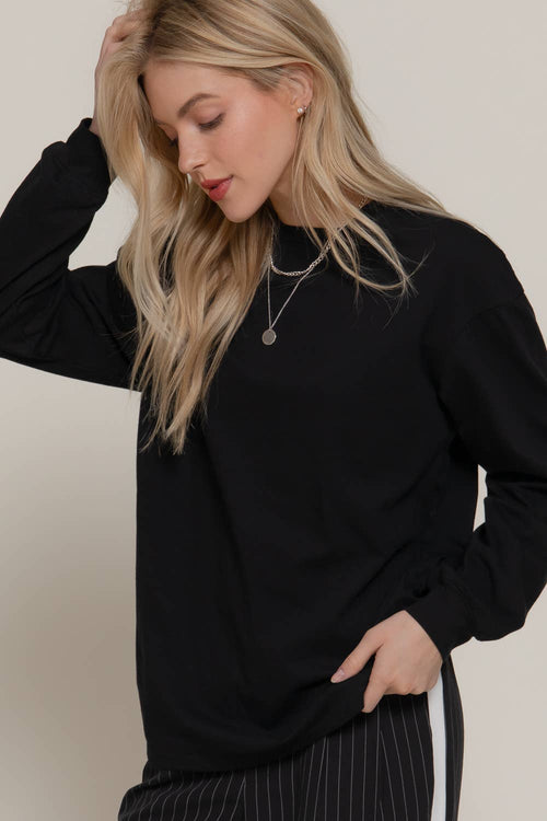 Woman wearing a black long-sleeve top against a plain background