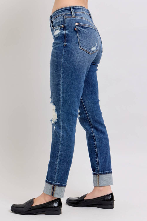 Blue jeans with a distressed look worn by a person on a white background