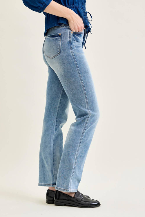 Person wearing light blue jeans and a blue top on a plain background