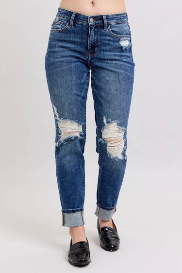 Distressed blue jeans worn by a person on a white background