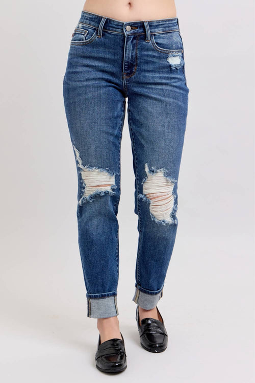 Distressed blue jeans worn by a person on a white background