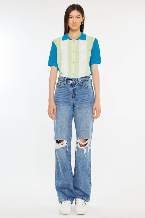 Person wearing a colorful striped shirt and ripped jeans on a white background