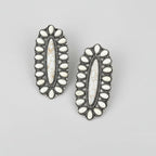 Pair of decorative earrings with white stones on a white surface