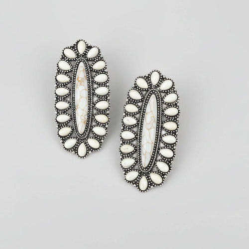 Pair of decorative earrings with white stones on a white surface