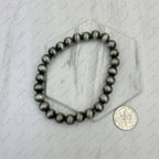 Black beaded bracelet on a marble surface with a coin for scale