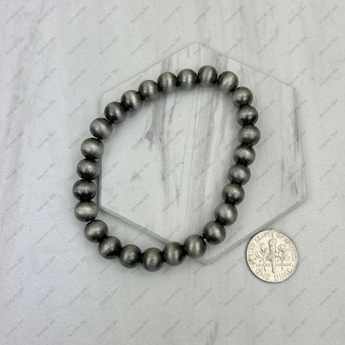 Black beaded bracelet on a marble surface with a coin for scale