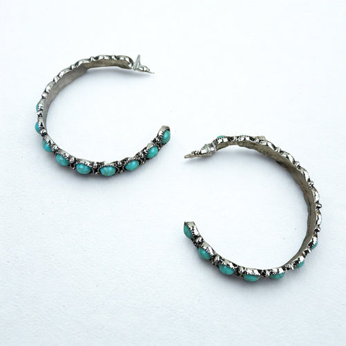 Pair of hoop earrings with turquoise stones on a white background
