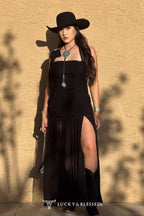 Woman in a black dress and cowboy hat against a beige wall with 'Lucky & Blessed' branding.