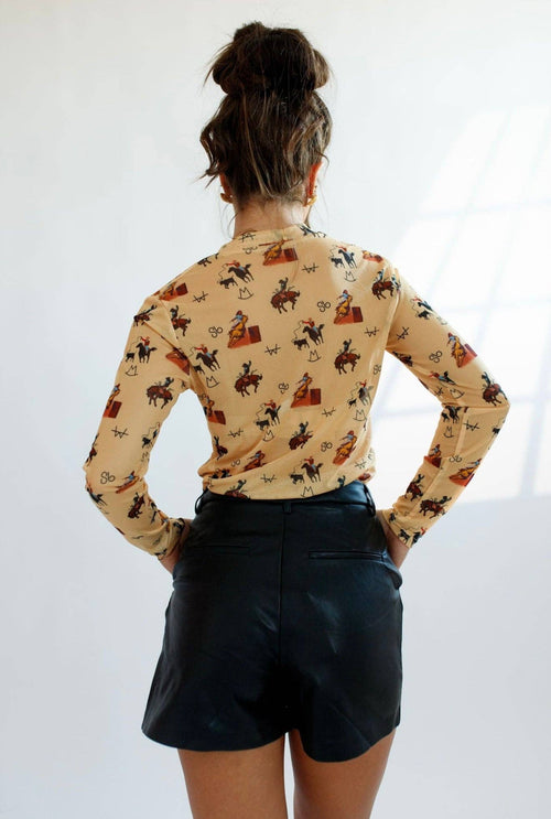 Person wearing a patterned long-sleeve shirt and dark shorts on a white background
