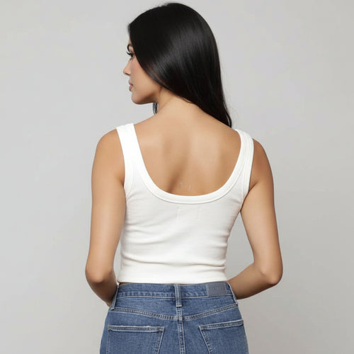 Woman wearing a white tank top and blue jeans.
