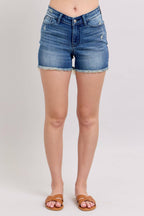 Person wearing blue denim shorts on a plain background