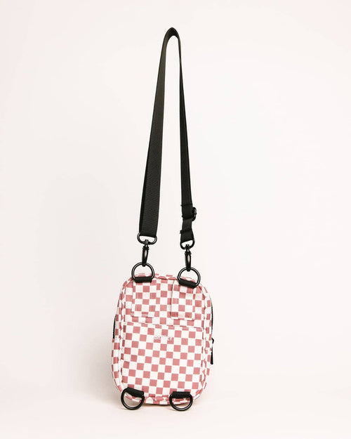 Small pink and white checkered bag with a black strap on a light beige background