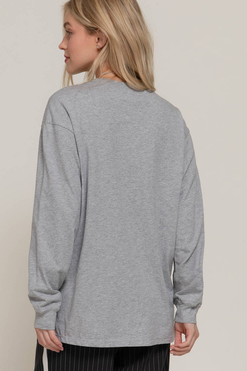 Person wearing a gray long-sleeve shirt against a plain background