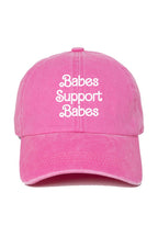 A pink baseball cap with the phrase 'Babes Support Babes' embroidered in white script across the front, shown against a plain white background.