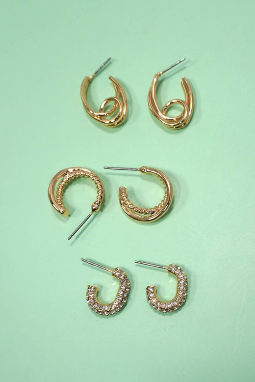 Set of gold hoop earrings on a light green background