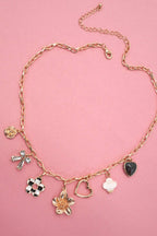 Gold necklace with various charms on a pink background