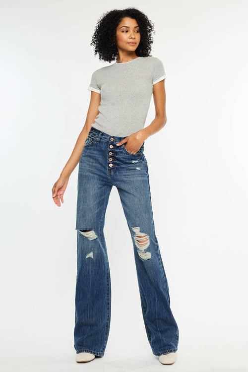 Woman wearing a gray t-shirt and blue jeans with button details on a white background
