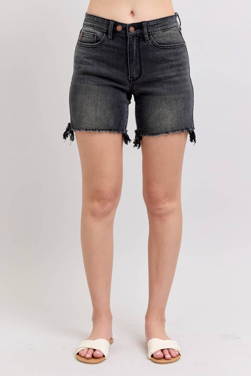 Black denim shorts worn by a person on a plain background