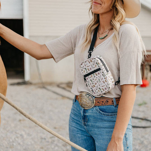Woman wearing a patterned crossbody bag and blue jeans with a belt