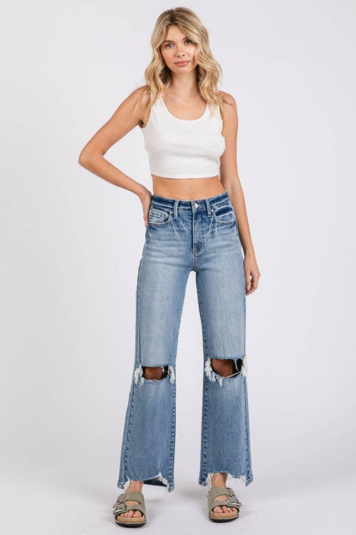 Woman wearing a white crop top and blue jeans with a white background