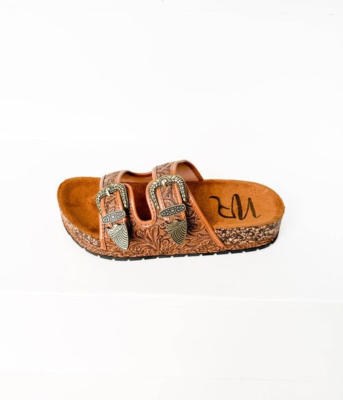 Brown sandal with decorative straps and 'MR' branding on a white background