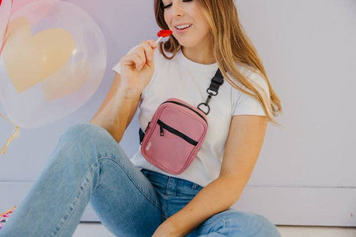 Woman holding a pink crossbody bag with a heart-shaped balloon in the background