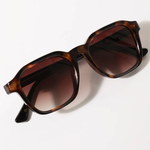 Sunglasses with tortoiseshell frame and brown lenses on a white background