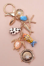 Keychain with various sea-themed charms on a pink background