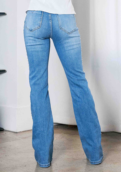 Blue jeans worn by a person on a plain background