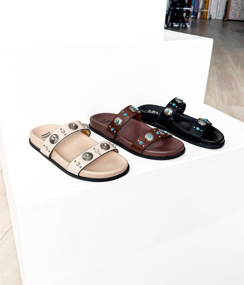 Three sandals in beige, brown, and black on a white surface.