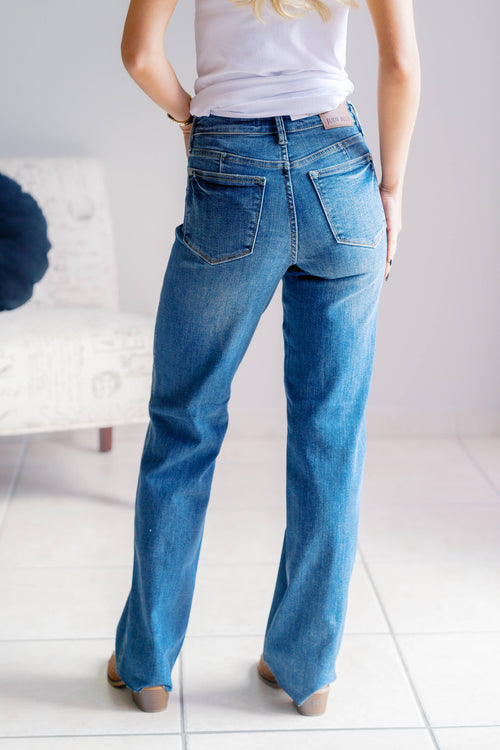 Person wearing blue jeans and a white shirt in a minimal indoor setting