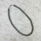 Black pearl necklace on a textured beige surface